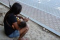 Woman cuddling sleeping little son clicking a mobile phone seated on church yard sidewalk