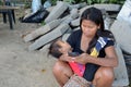 Woman cuddling sleeping little son clicking a mobile phone seated on church yard sidewalk