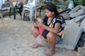 Woman cuddling sleeping little son clicking a mobile phone seated on church yard sidewalk