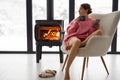 Woman with cup on chair by the fireplace at house on nature