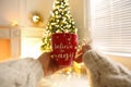Woman With Cup Of Drink And Blurred Christmas Tree On Background, Closeup