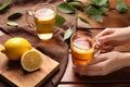 Woman with cup of fresh iced tea at wooden table, closeup