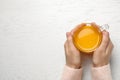 Woman with cup of fresh sea buckthorn tea at white wooden table, top view. Space for text Royalty Free Stock Photo