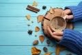 Woman with cup of hot drink at light blue wooden table, top view. Cozy autumn atmosphere Royalty Free Stock Photo
