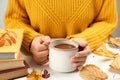 Woman with cup of hot drink at white wooden table, closeup. Cozy autumn atmosphere Royalty Free Stock Photo