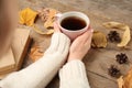 Woman with cup of hot drink at wooden table, closeup. Cozy autumn atmosphere Royalty Free Stock Photo