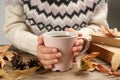 Woman with cup of hot drink at wooden table, closeup. Cozy autumn atmosphere Royalty Free Stock Photo