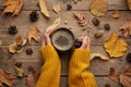 Woman with cup of hot drink at wooden table, top view. Cozy autumn atmosphere Royalty Free Stock Photo