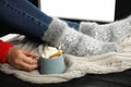 Woman with cup of hot winter drink with whipped cream sitting on window sill