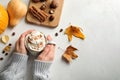 Woman with cup of tasty pumpkin spice latte at light table. Space for text