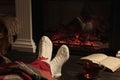 Woman with cup of tea and book resting near fireplace at home, closeup Royalty Free Stock Photo