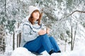 Woman with a cup of tea in her hands siting in in snow-covered forest