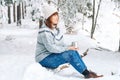 Woman with a cup of tea in her hands siting in in snow-covered forest