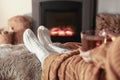 Woman with cup of tea resting near fireplace at home, closeup Royalty Free Stock Photo