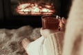 Woman with cup of tea resting near fireplace at home, closeup Royalty Free Stock Photo