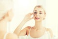 Woman with curler curling eyelashes at bathroom