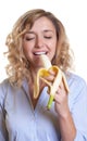 Woman with curly blond hair eating a sweet banana