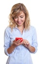 Woman with curly blond hair writing message with phone Royalty Free Stock Photo