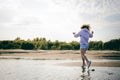 Woman with curly hair, the romance of youth, a journey walk on a warm summer sunny day on a sandy beach with water Royalty Free Stock Photo