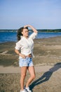 Woman with curly hair, the romance of youth, a journey walk on a warm summer sunny day on a sandy beach with water Royalty Free Stock Photo