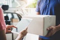 Woman customer appending signature in digital tablet and receiving a cardboard boxes parcel from delivery service courier, Home d