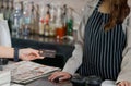 Woman customer hand send a credit card to a waitress for pay a coffee drink at counter bar