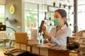 Woman customer with protective mask paying bill by cell phone in cafe. Royalty Free Stock Photo