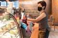 Woman customer with protective mask paying bill by cell phone in cafe. Royalty Free Stock Photo