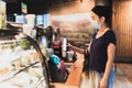 Woman customer with protective mask paying bill by cell phone in cafe. Royalty Free Stock Photo