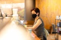 Woman customer with protective mask paying bill by cell phone in cafe. Royalty Free Stock Photo