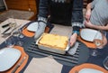 Woman cut with knife hot tasty home baking lasagna in ceramic casserole dish Royalty Free Stock Photo