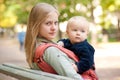 Woman and cute baby sitting on bench in park