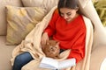 Woman with cute cat reading book at home on autumn day Royalty Free Stock Photo
