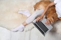 Woman with cute red cat and laptop on fur carpet. Space for text Royalty Free Stock Photo