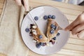 Woman with cutlery eating traditional pancakes with fresh blueberries and agave syrup on a plate. Breakfast outside on Royalty Free Stock Photo