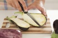 Woman cuts eggplant on cutting board in kitchen.