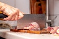 A woman cuts fish with a large knife at home in the kitchen