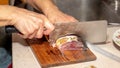 A woman cuts fish with a large knife at home in the kitchen