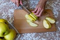 Woman cuts by knife an apple to slices on a cutting board on a table in the kitchen. Chantecler apples Royalty Free Stock Photo