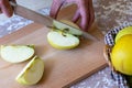 Woman cuts by knife an apple to slices on a cutting board on a table in the kitchen. Chantecler apples Royalty Free Stock Photo