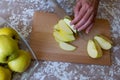 Woman cuts by knife an apple to slices on a cutting board on a table in the kitchen. Chantecler apples Royalty Free Stock Photo