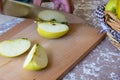 Woman cuts by knife an apple to slices on a cutting board on a table in the kitchen. Chauntecleer apples Royalty Free Stock Photo