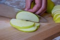 Woman cuts by knife an apple to slices on a cutting board on a table in the kitchen. Chauntecleer apples Royalty Free Stock Photo