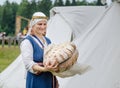 Woman cuts loaf of large bread on wooden table