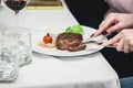 Woman cuts a piece of fresh grilled bbq roast beef steak. soup sauce small jug glass served on a table in a restaurant Royalty Free Stock Photo