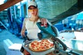a woman cuts a pizza with a circular saw.