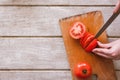 Woman cuts red tomato on parts on wooden desk