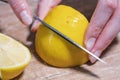 Woman cuts ripe lemon with silver knife, close-up