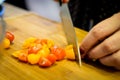 A woman cuts small colorful plum tomatoes on a cutting board. Cooking.