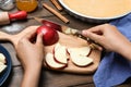 Woman cutting apple at wooden table, closeup. Baking pie